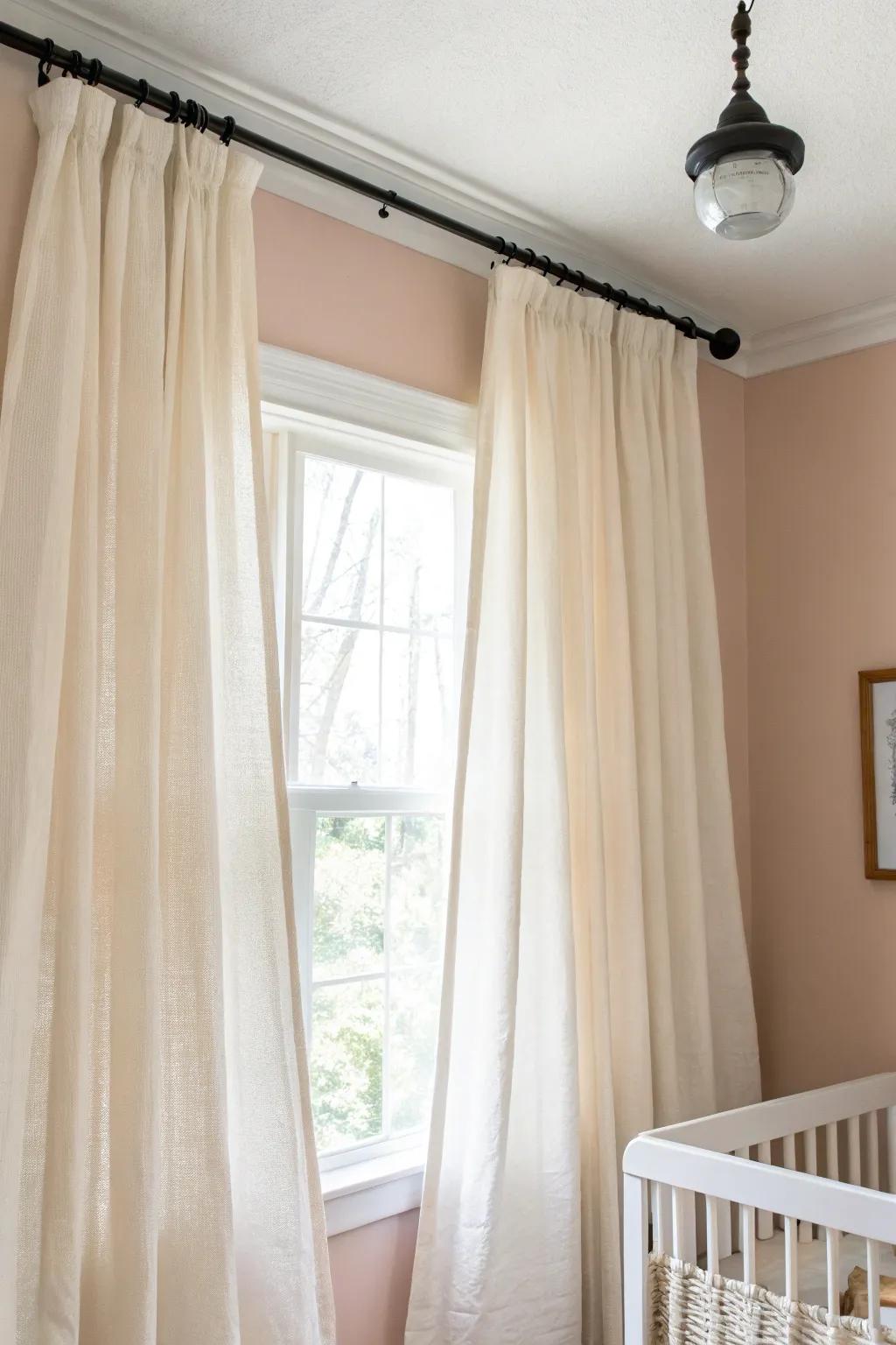 Ceiling-high linen curtains draw the eye up, making a tiny baby girl nursery feel taller and airy.