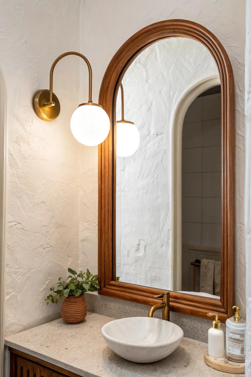A centered brass globe sconce above an arch mirror—minimal, boutique, and warmly glowing.