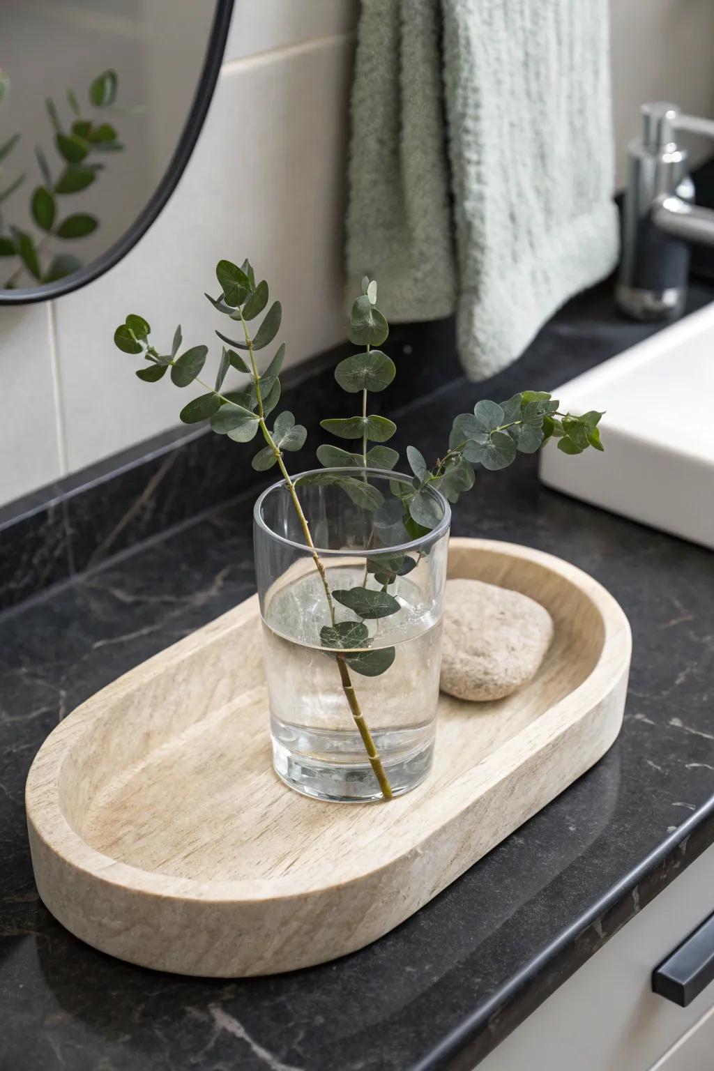 Green stems in a simple water glass on a vanity tray—fresh, rental-friendly, and chic.