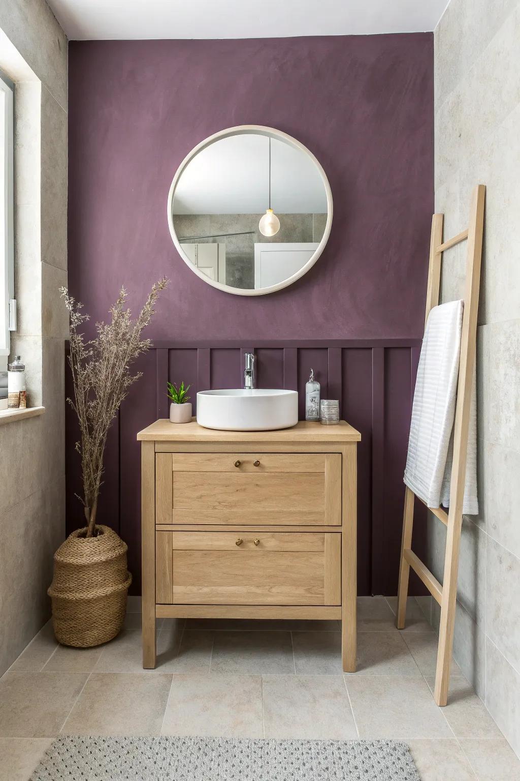 A plum accent wall behind a petite oak vanity adds drama without shrinking the space.