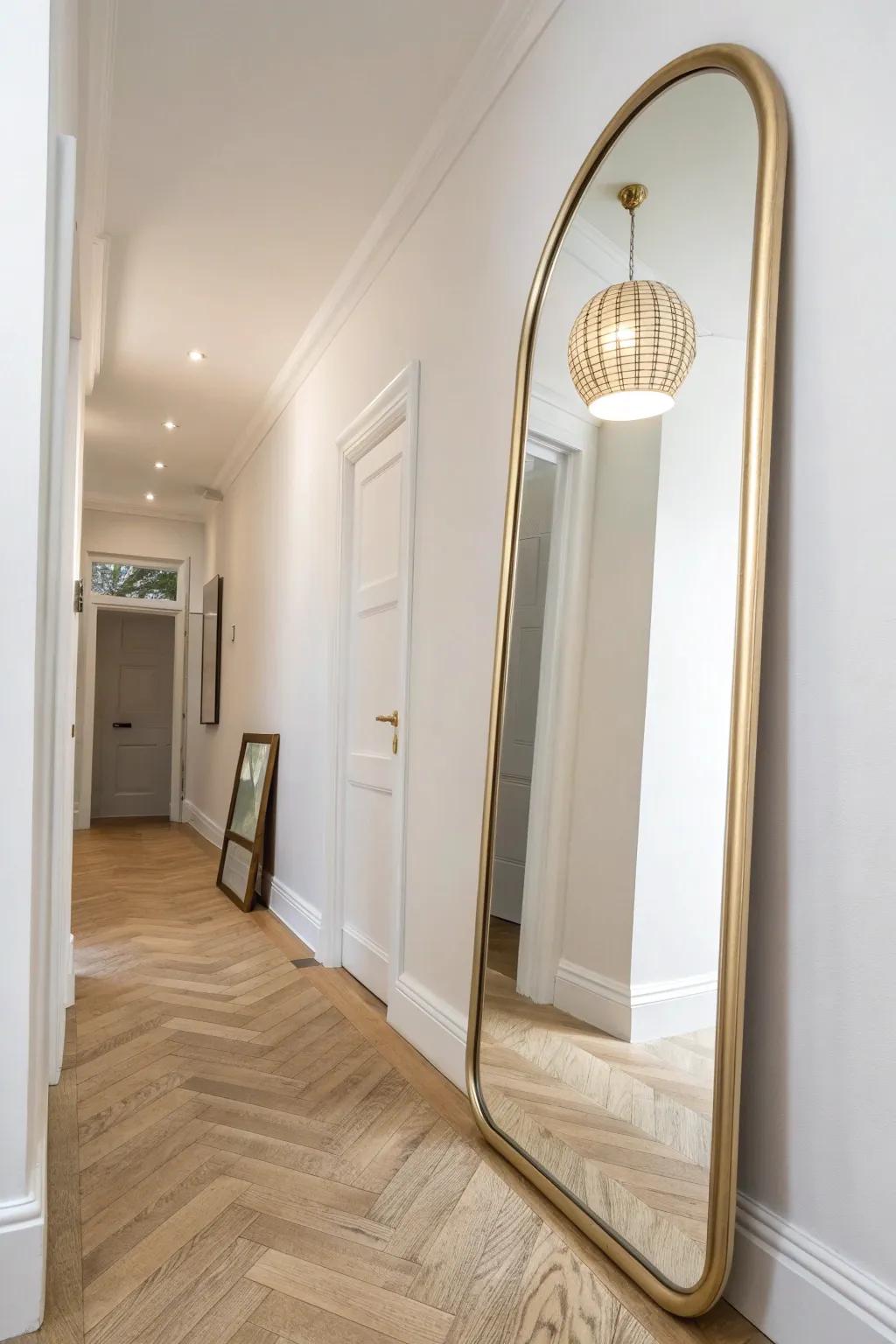 An oversized arched mirror reflects warm light, making a narrow hallway feel instantly wider.
