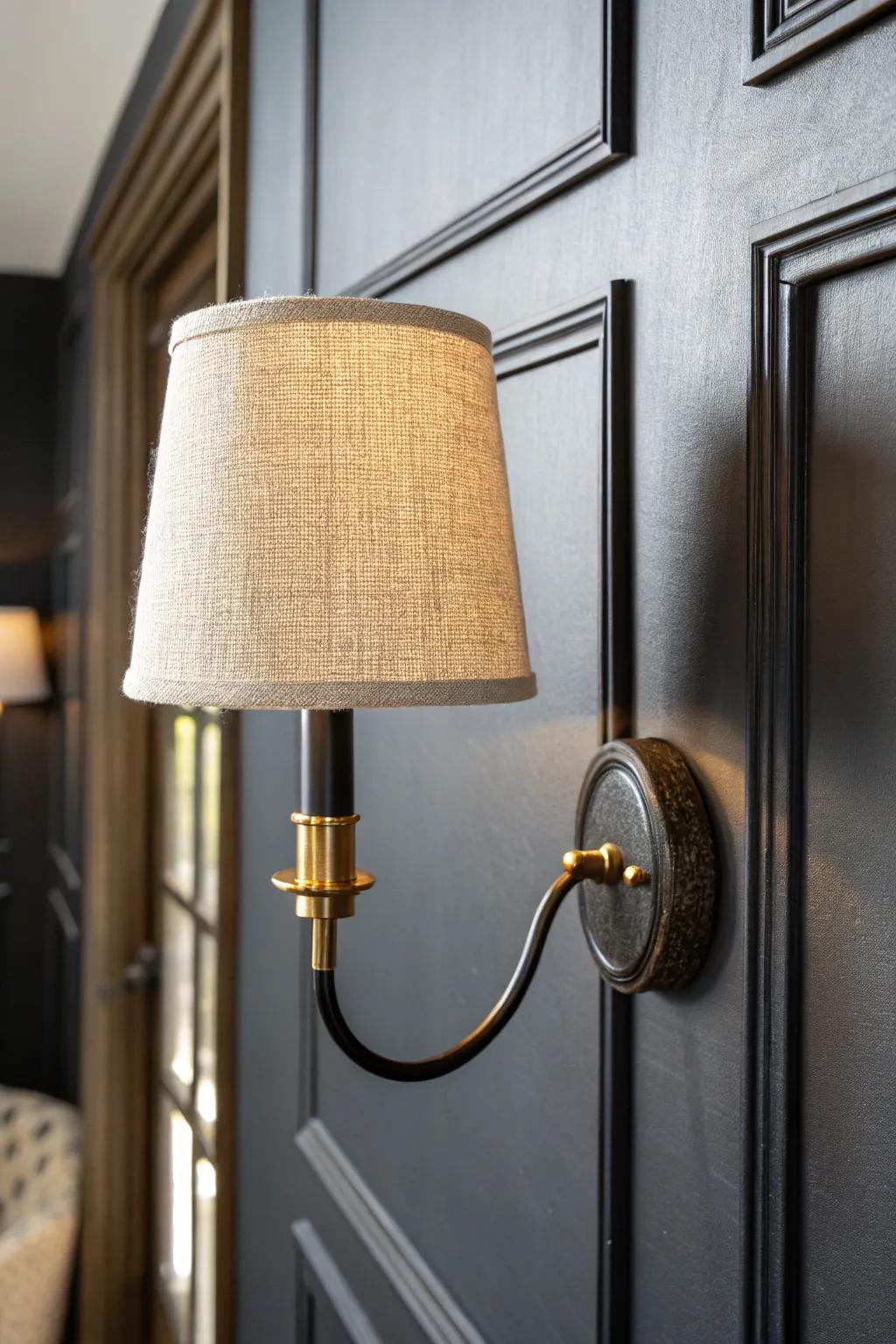 Matte-black wall sconce + warm brass glow: big style for small black bedrooms, zero nightstand clutter.