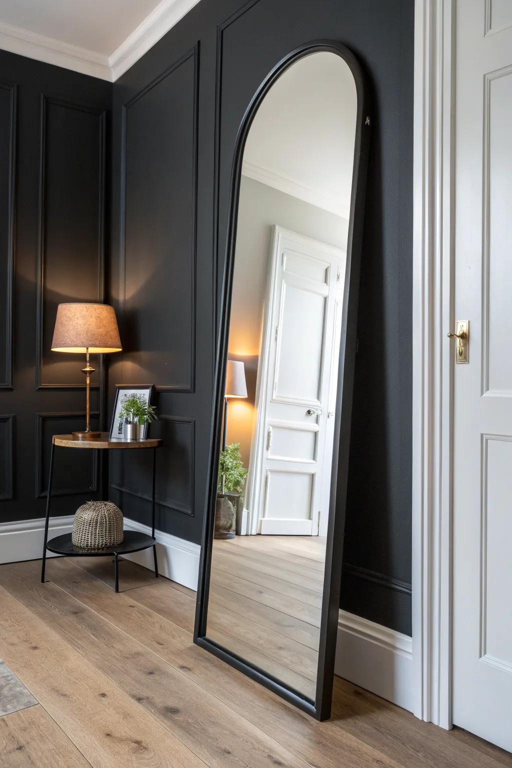 A tall arched mirror bounces lamp glow around a black hallway, instantly making it feel brighter.