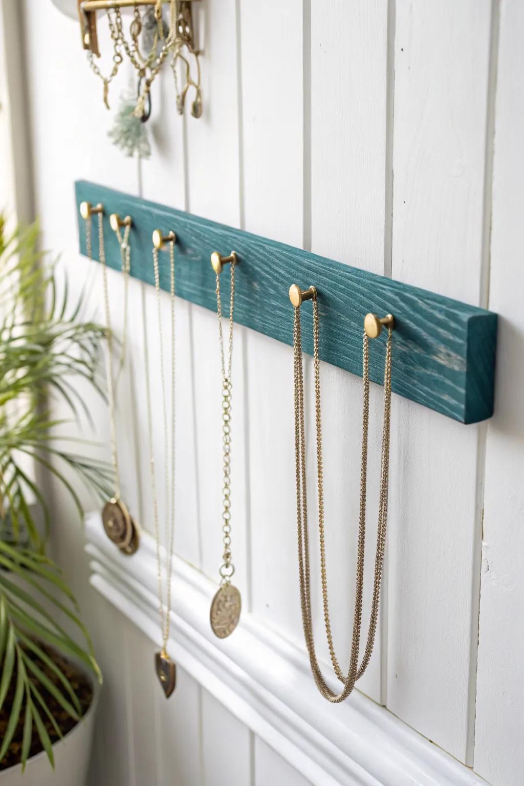 DIY knob-and-slat necklace strip: bold painted slat + brass knobs keeps chains tangle-free.