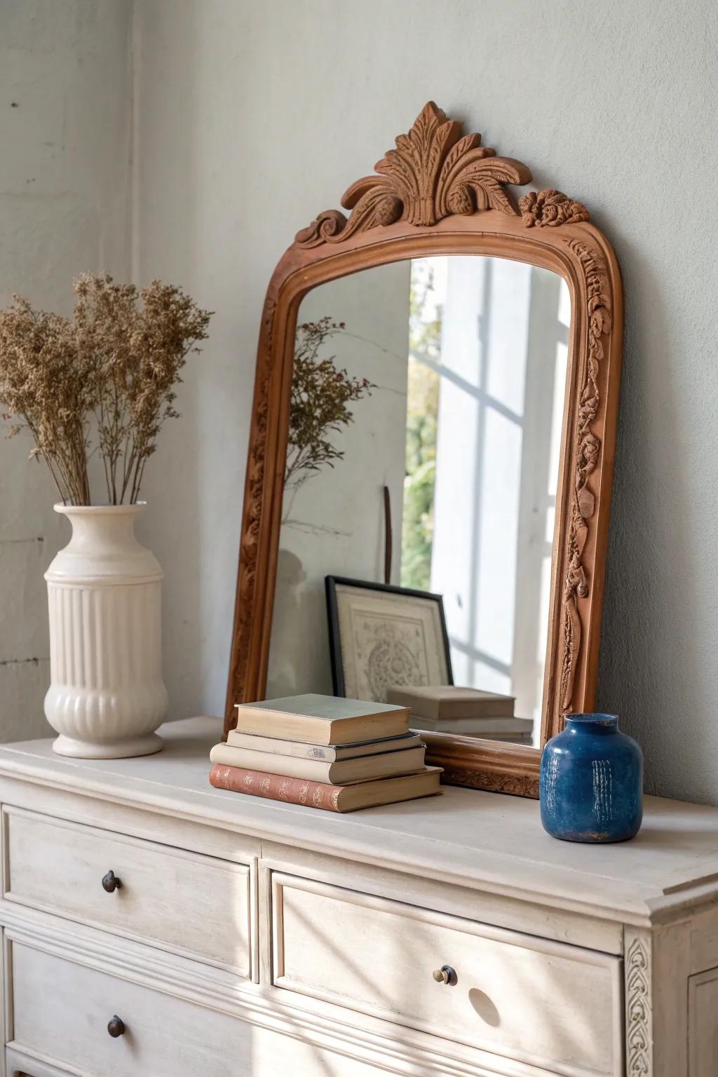 A vintage dresser mirror above a mantel—styled with books and a tall vase for balance.