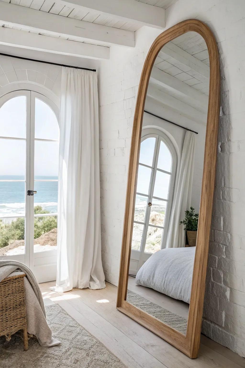 Lean an oversized arched mirror to reflect the window and instantly brighten a tiny coastal bedroom.